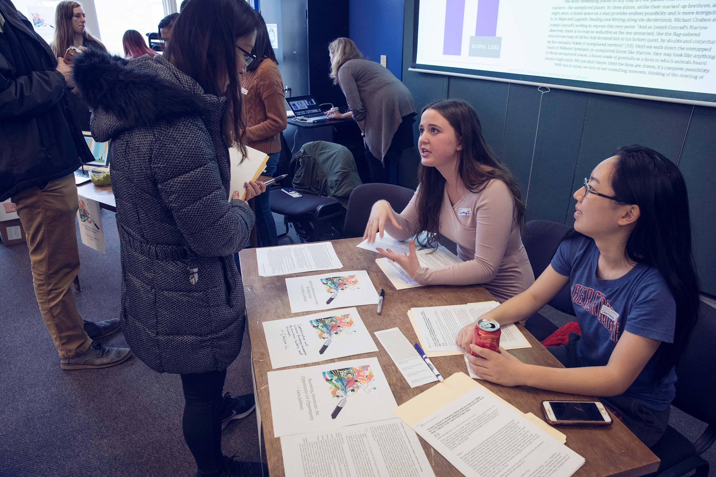 Courtny Cushman, left, and Chelsea Li, right talk to a person at their table