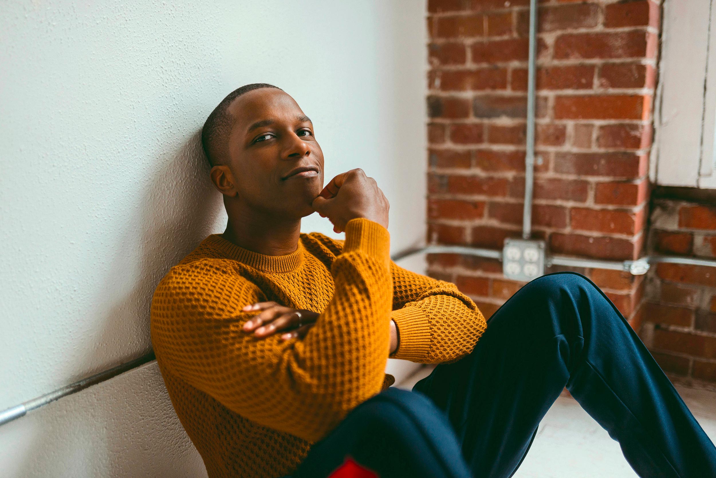 Leslie Odom Jr. sits on the floor looking at the camera