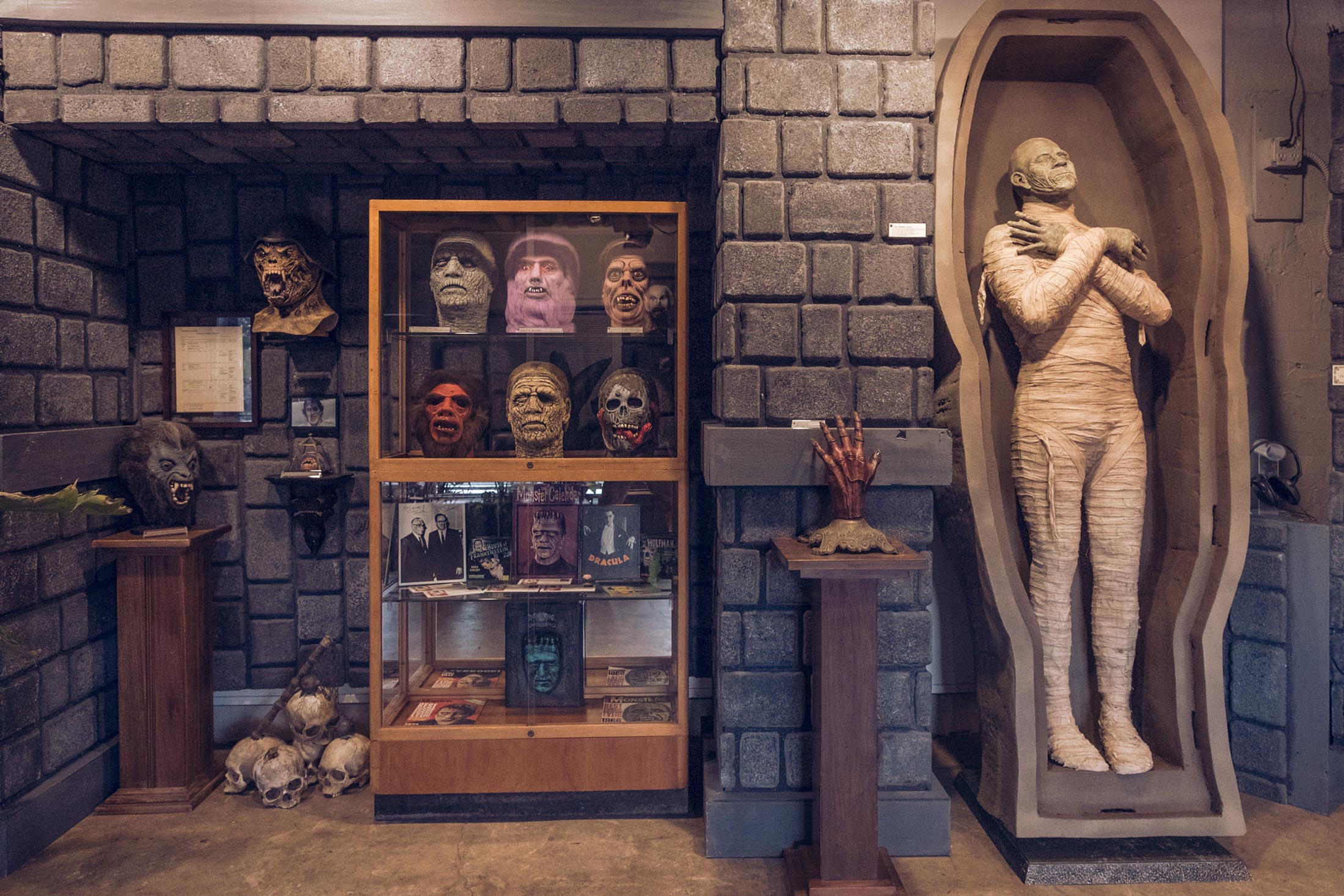 Monster masks and a model mummy on display in an art gallery