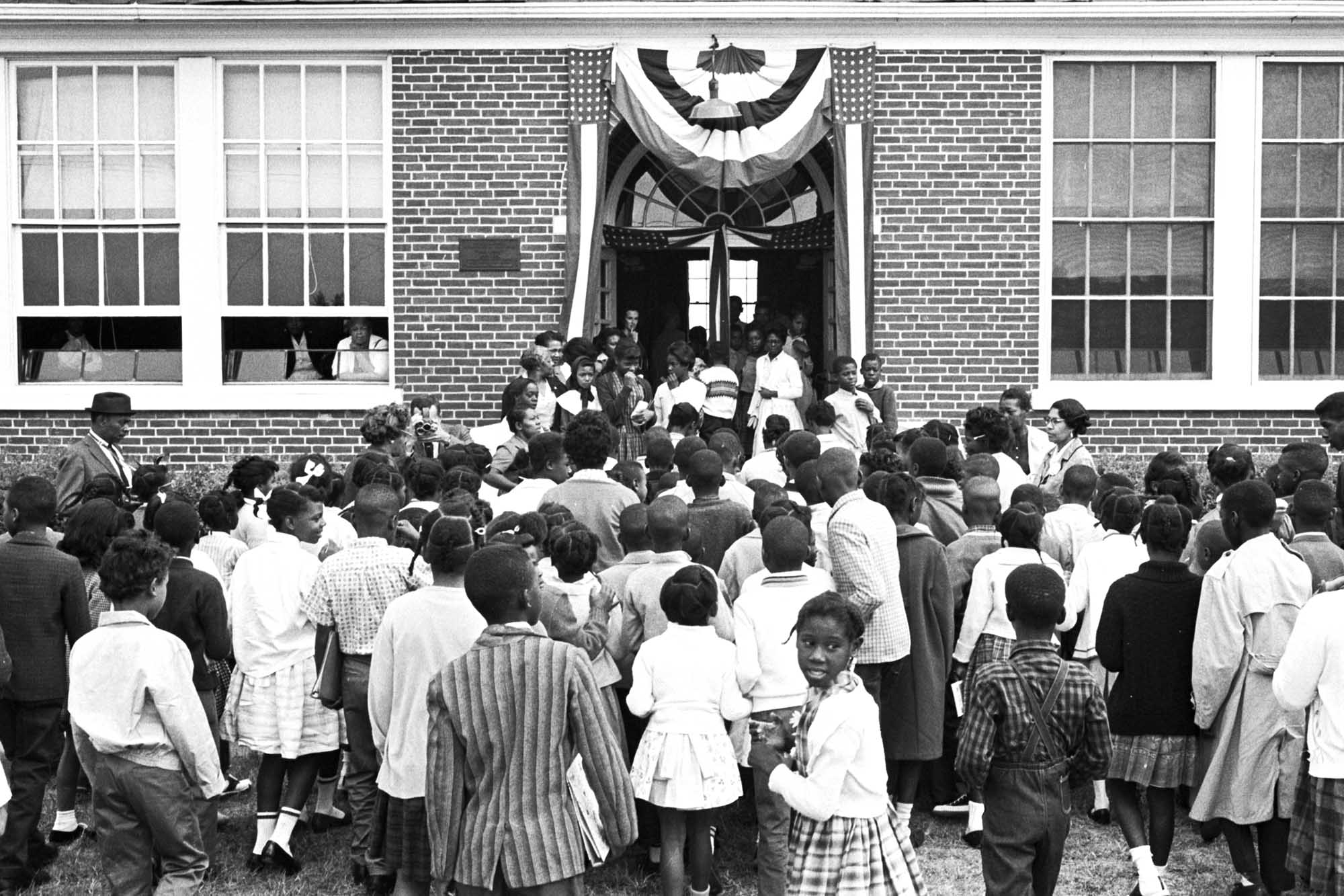 Brick school building with African American children walking into the school building