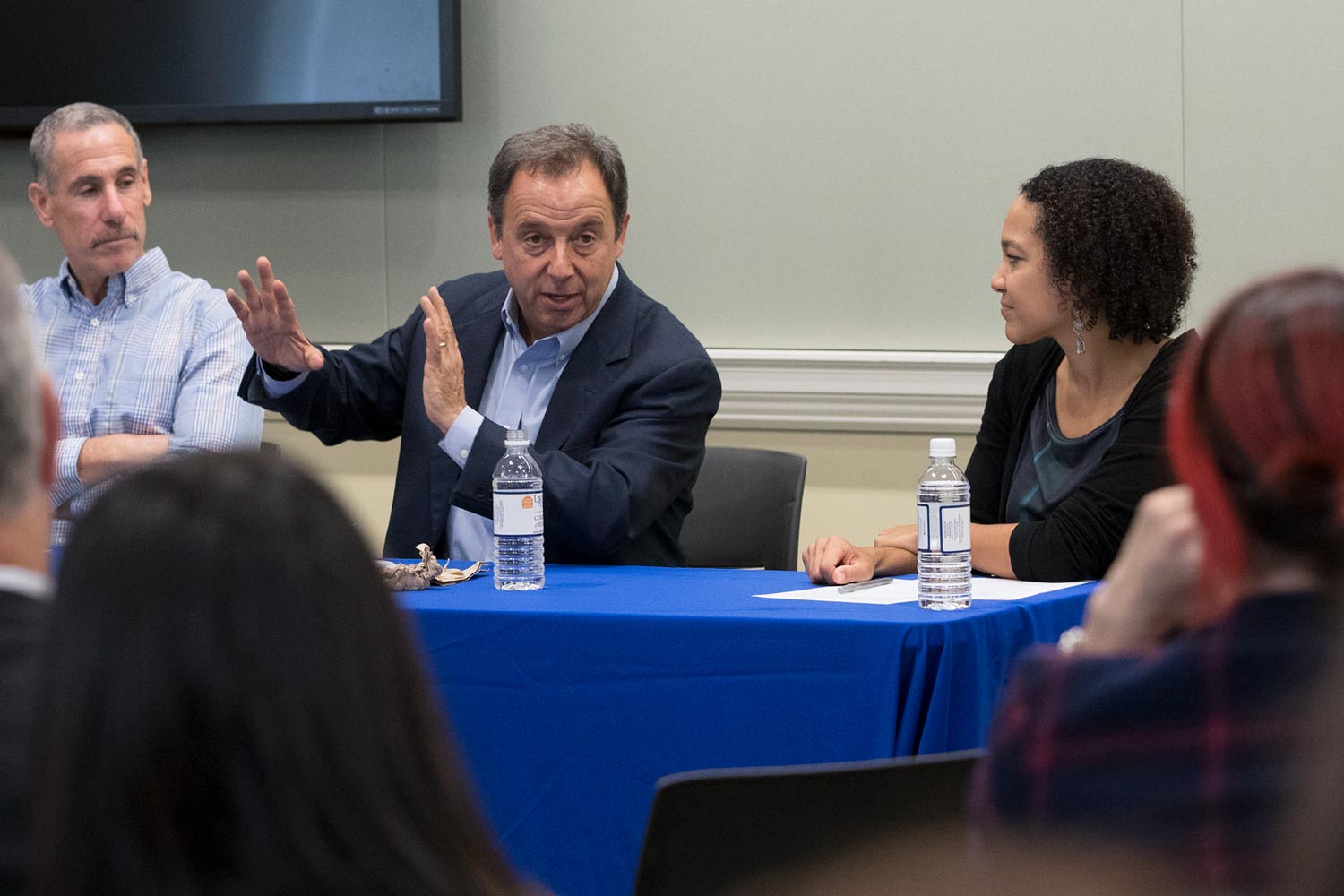 Ronald Suskind sits at a table with other panelists talking to a crowd