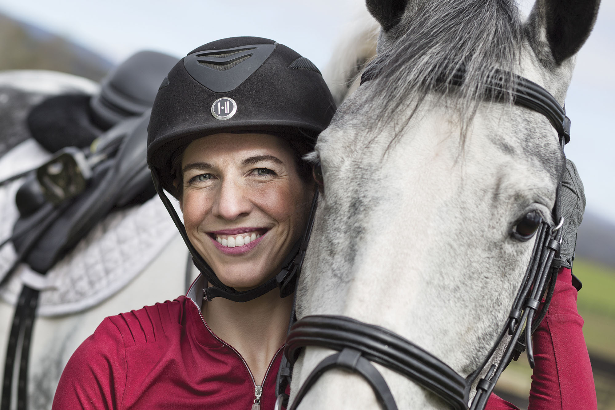 Stephanie Bajo headshot while she holds her white horses head