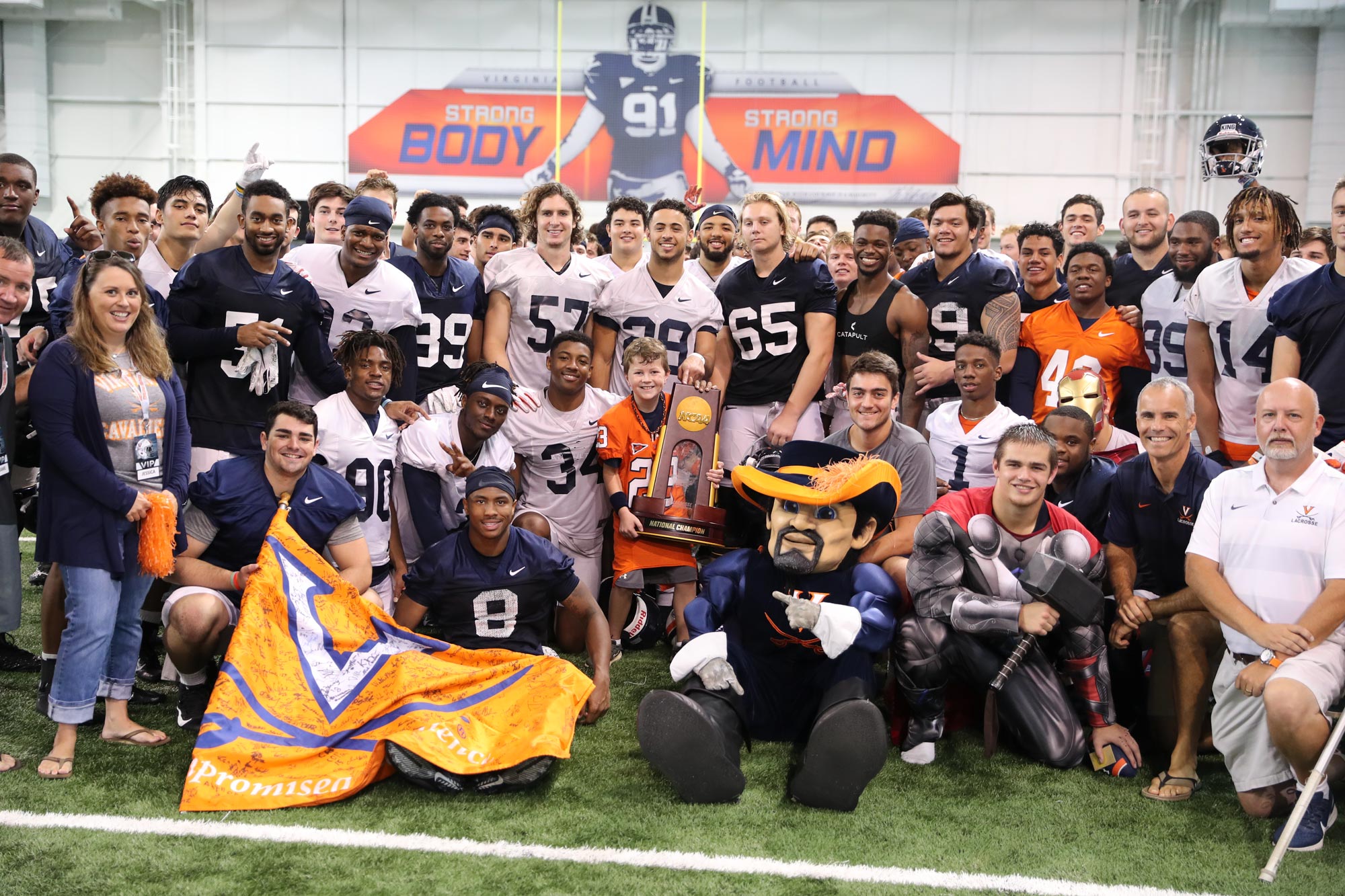 The UVA football program poses with children for a picture