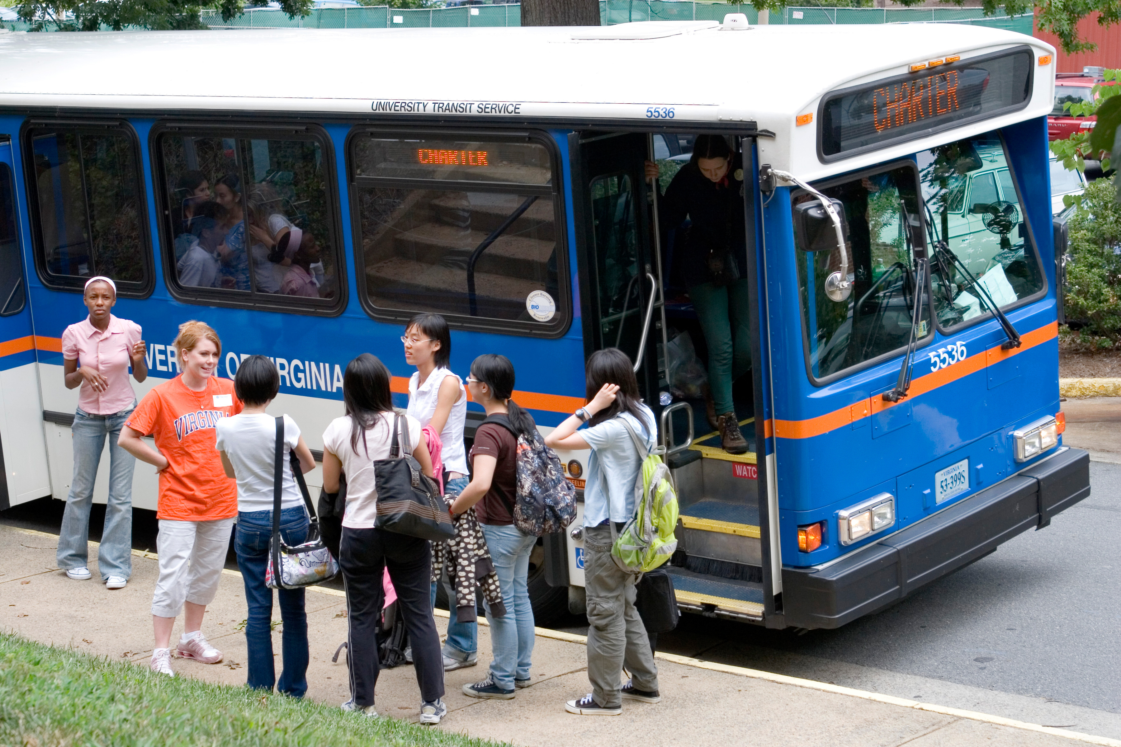 Students stand beside of a UVA bus on the sidewalk