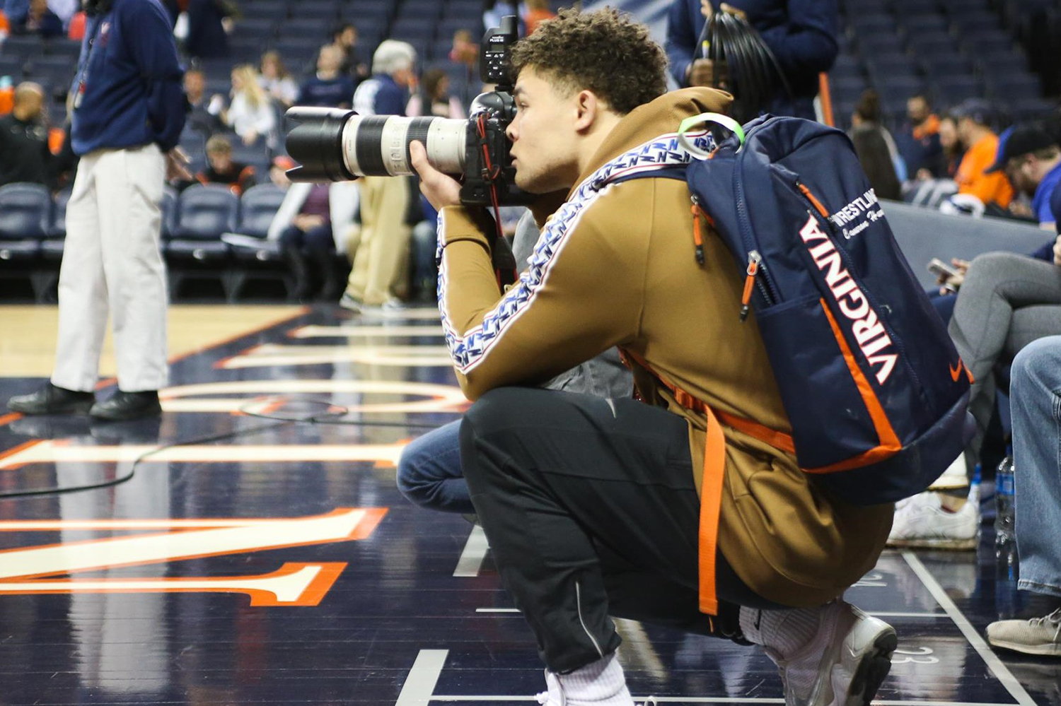Cam Harrell on the sidelines of a basketball court taking pictures