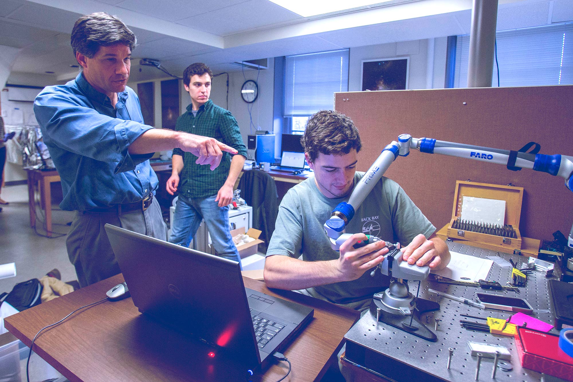 Instrument scientist John Wilson discusses a process with astronomy undergraduate Brady Anthony-Brumfield. Astronomy alumnus and lab technician Matt Hall, background, worked on APOGEE.