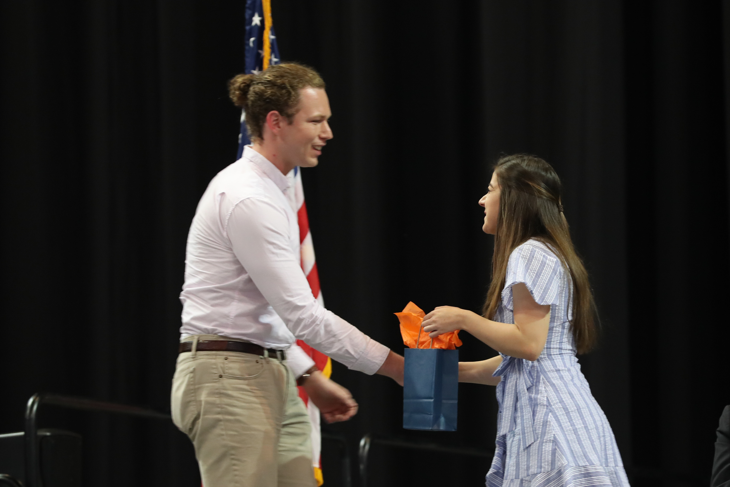Austin Widner recieving a blue bag from a woman on stage