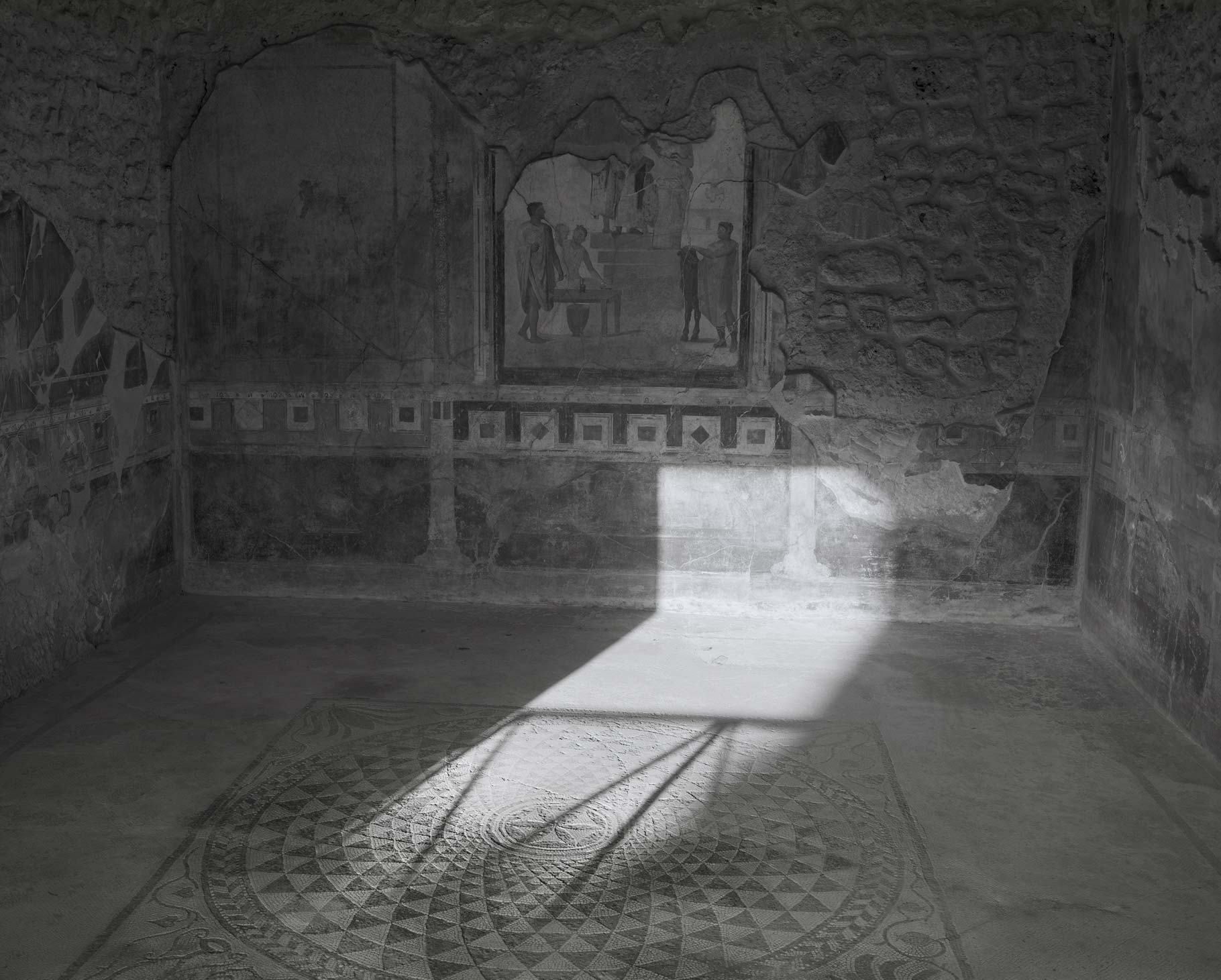 Inside of a room with intricate art on the walls in pompeii, black and white image