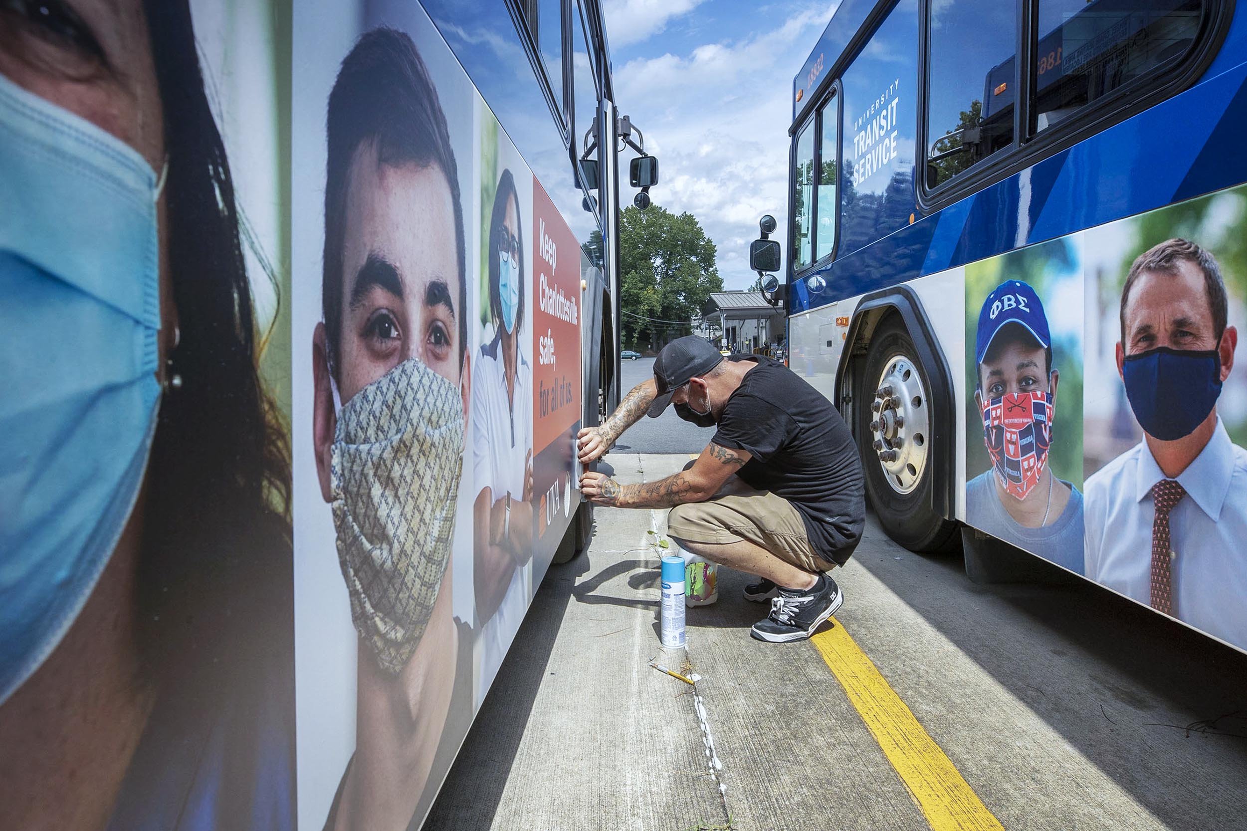 Staff member adding new signage to the outside of the UVA Transportation busses