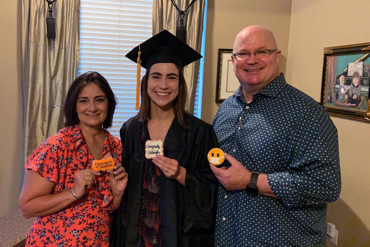 Ceileigh Holsteen with her parents each holding cookies decorated for graduation