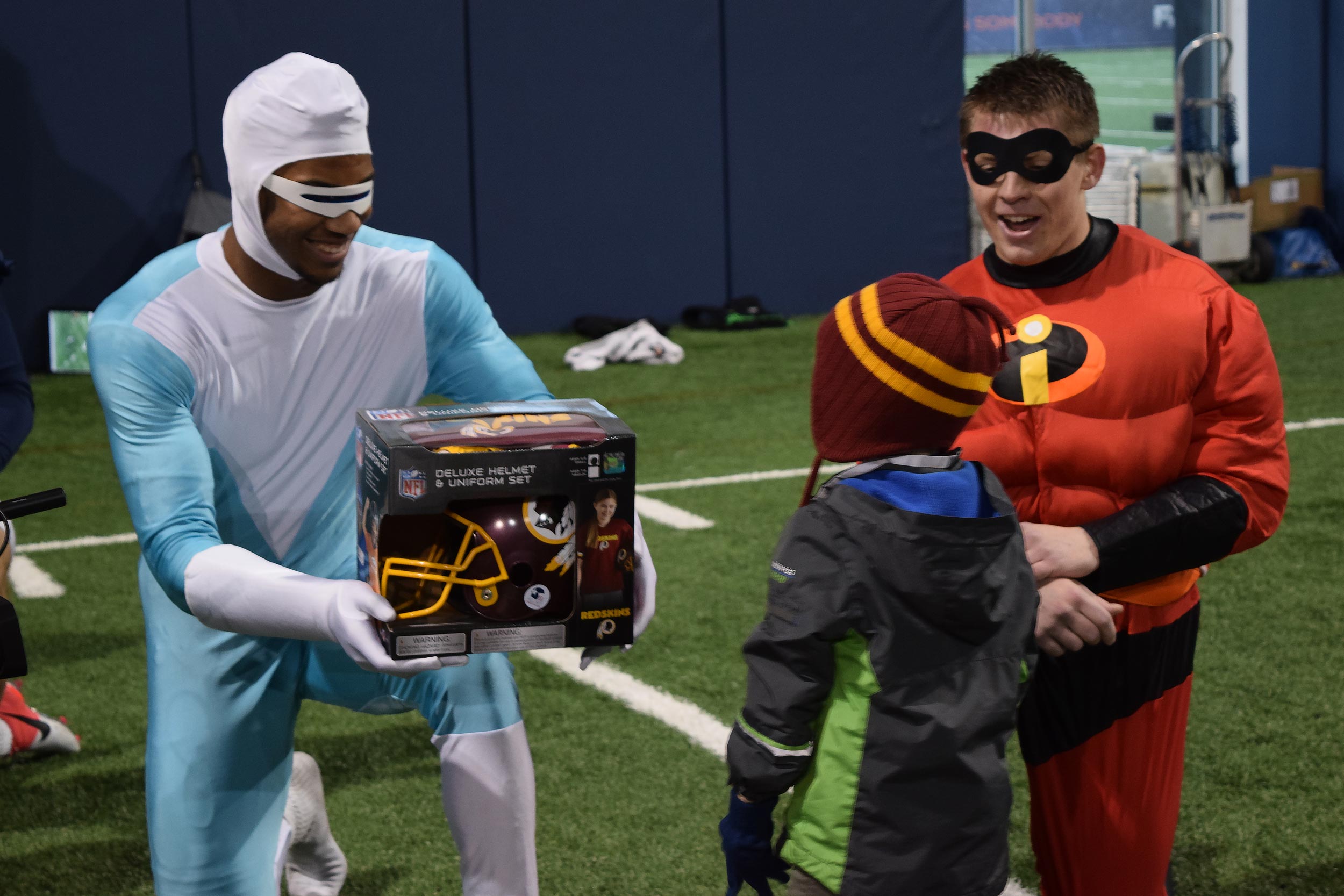 Snowden, left, dressed as Frozone from “The Incredibles” handing a football helmet to a child