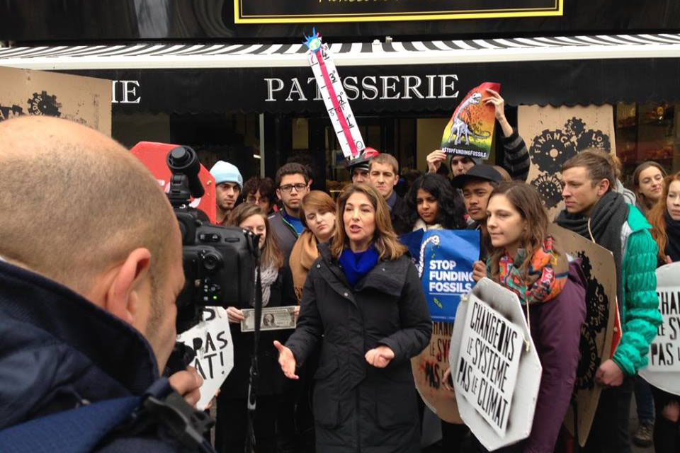 Cross stands to the left of speaker Naomi Klein, an award-winning journalist and syndicated columnist speaking to reporters in Paris about the damages of climate change.