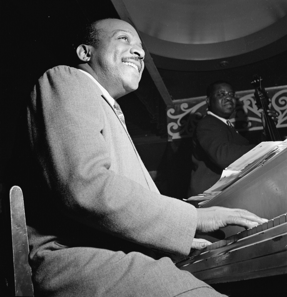 Count Basie, playing the piano in a black and white image