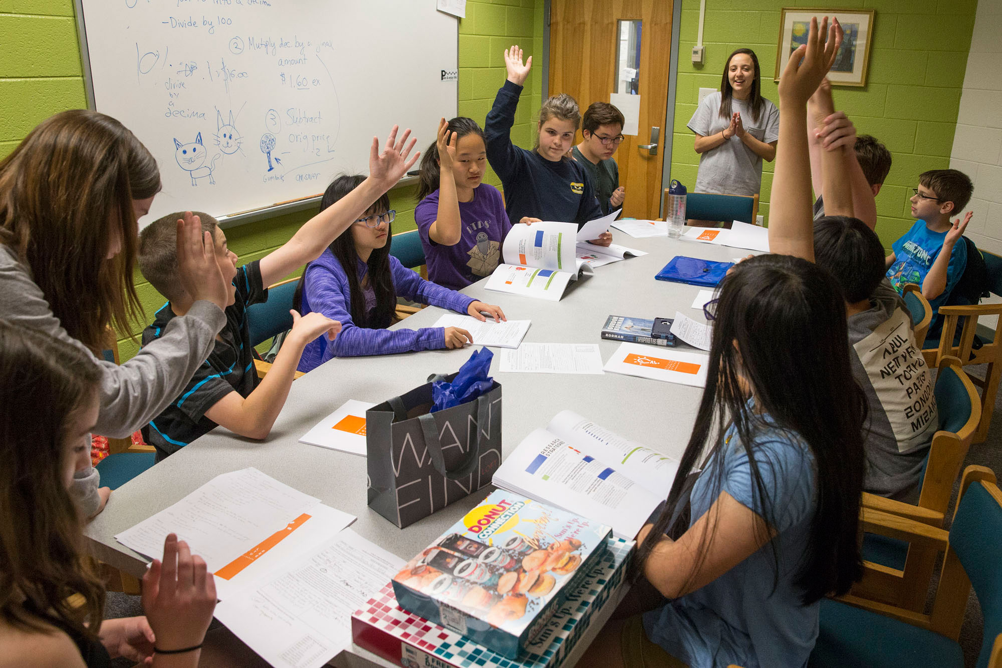 Second-year UVA student Victoria Farris (standing) coaches Sutherland Middle School students in the Charlottesville Debate League that Parisa Sadeghi started several years ago. (Photo by Dan Addison) 
