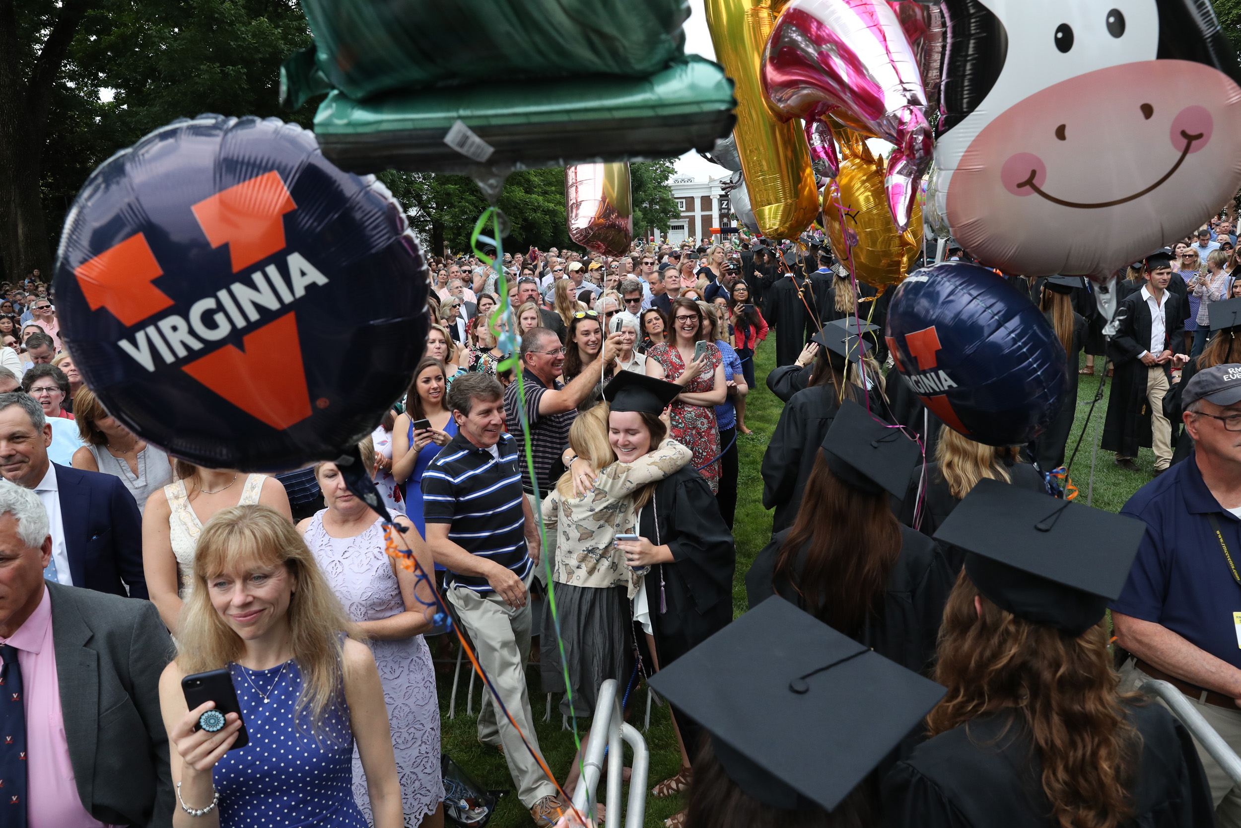 Graduates walk down the lawn and hug family members