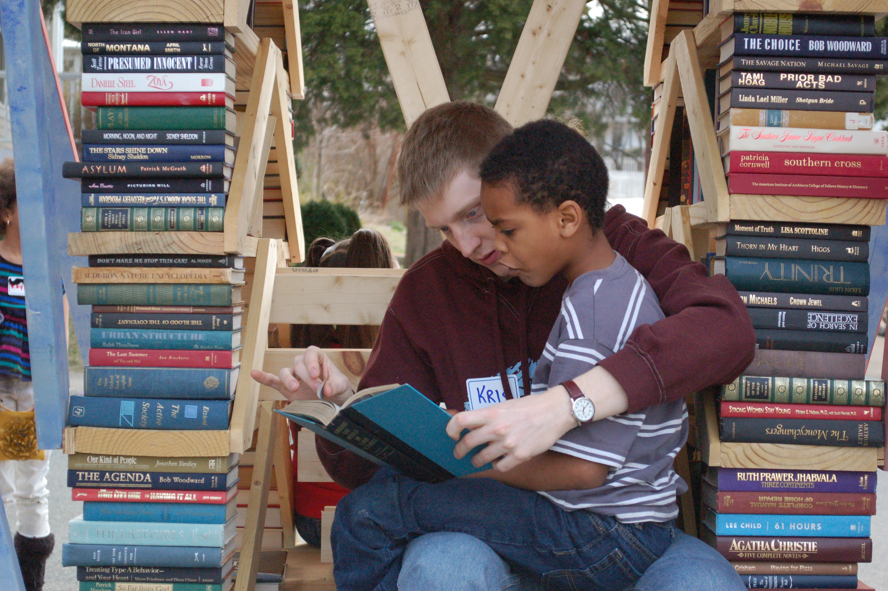 Man holds a little boy on his lap as they read a book together