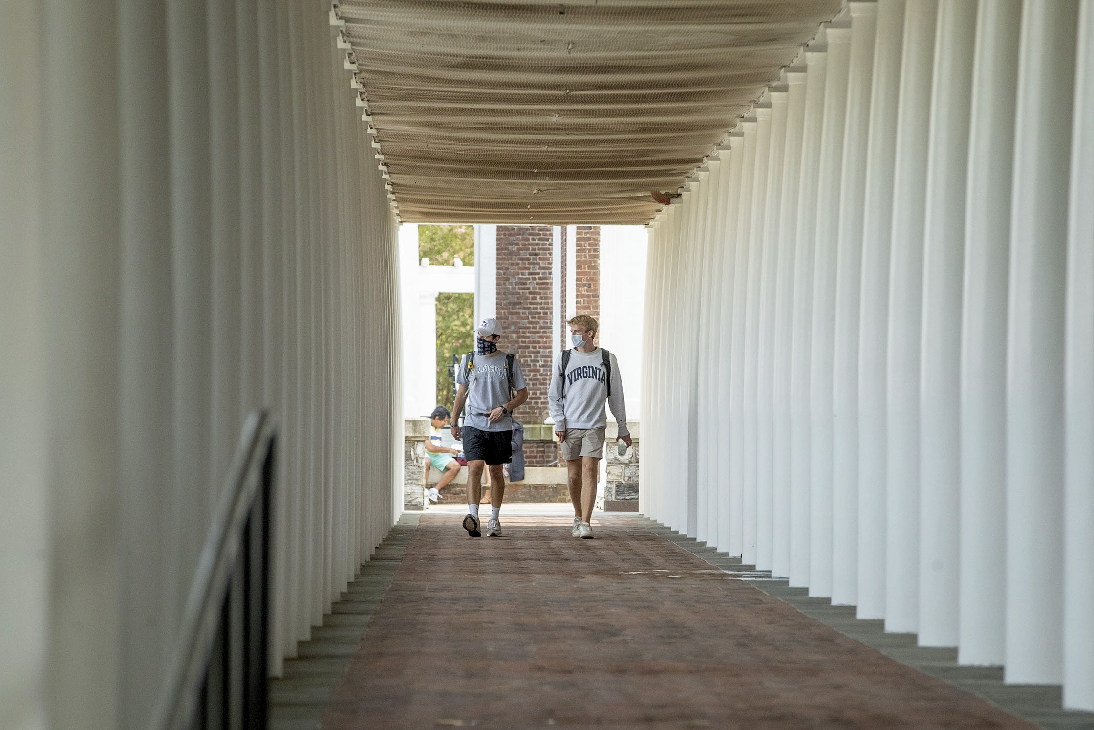 Students walking on a sidewalk lined with white columns