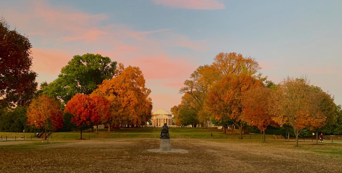 Rotunda in the distance surrounded by red, orange, yellow, and green trees and pink clouds on a blue sky