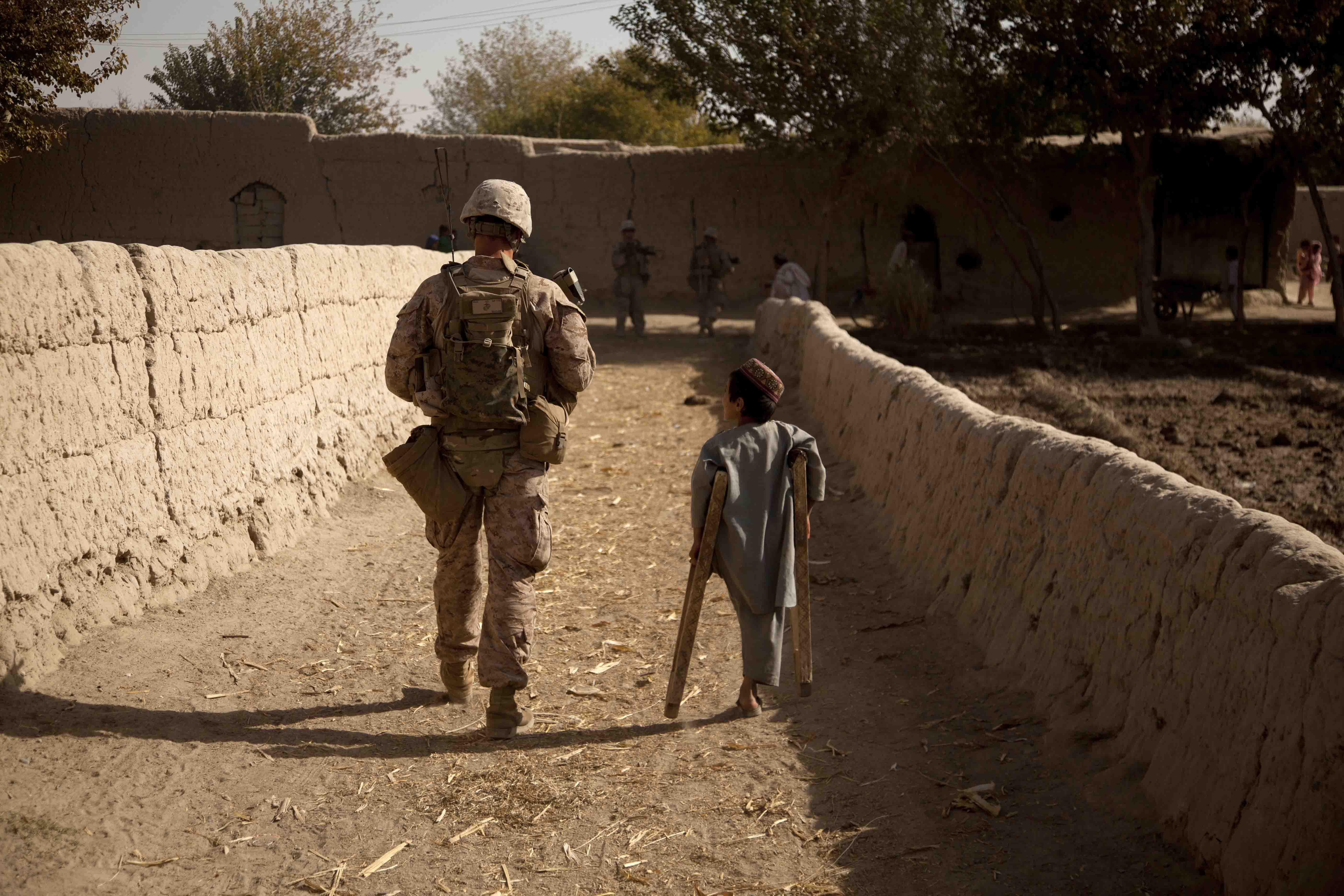 India Company’s Cpl Jacob Marler patrols through the Southern Green Zone alongside one of the many Afghan children caught in the struggle between the Marines and the Taliban. (U.S. Marine Corps photo by LCpl Armando Mendoza)
