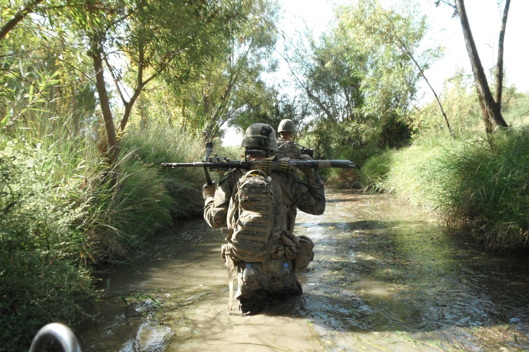 The safest, and least comfortable, route. Kilo Company&#039;s LCpl Casey Allison patrols with 1st Platoon through one of the Northern Green Zone’s ubiquitous canals - the only place sure to be free of IEDs. (Photo courtesy of Seth Folsom.)