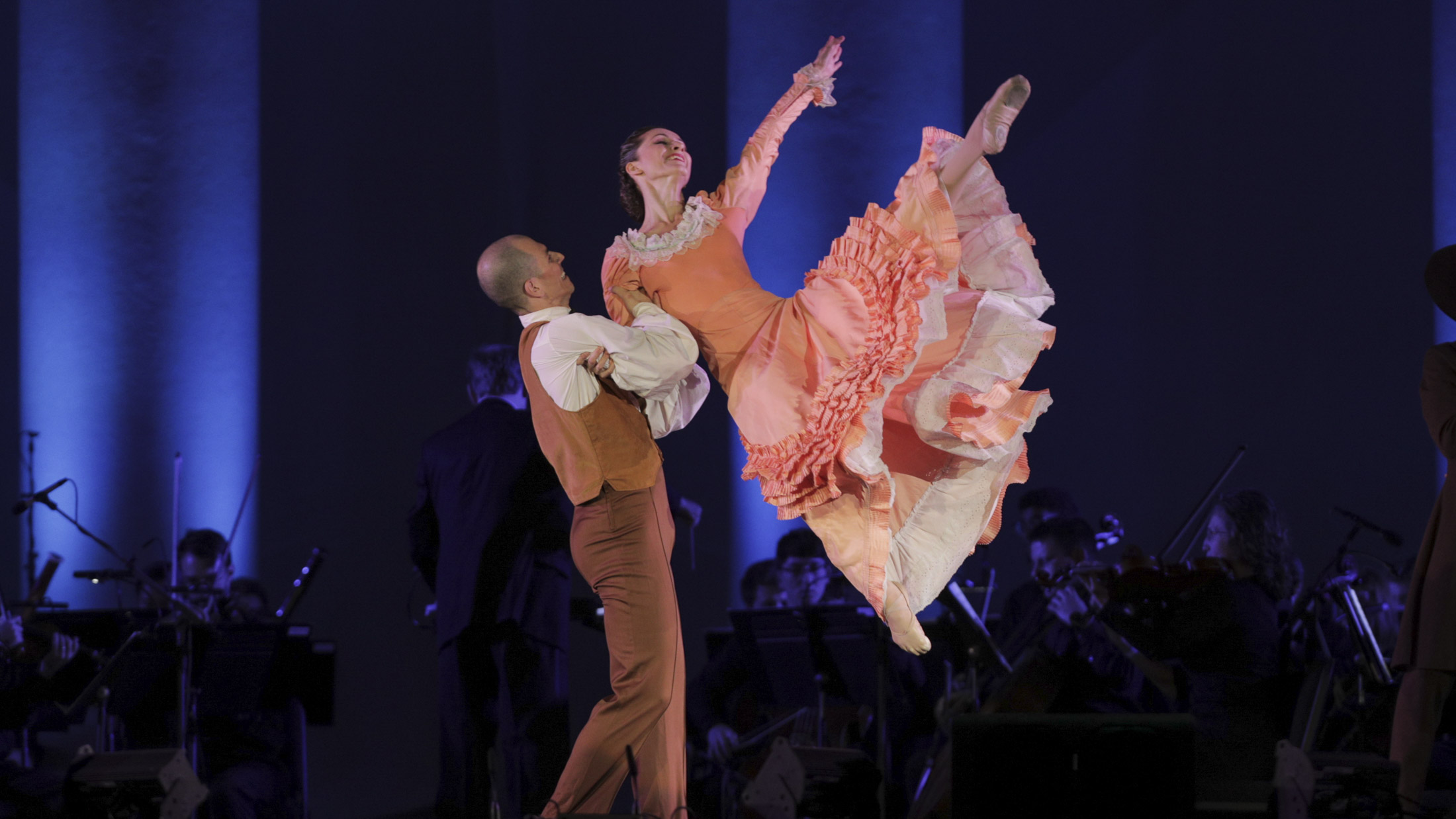 Man lifting a female dancer in a pink dress in the air