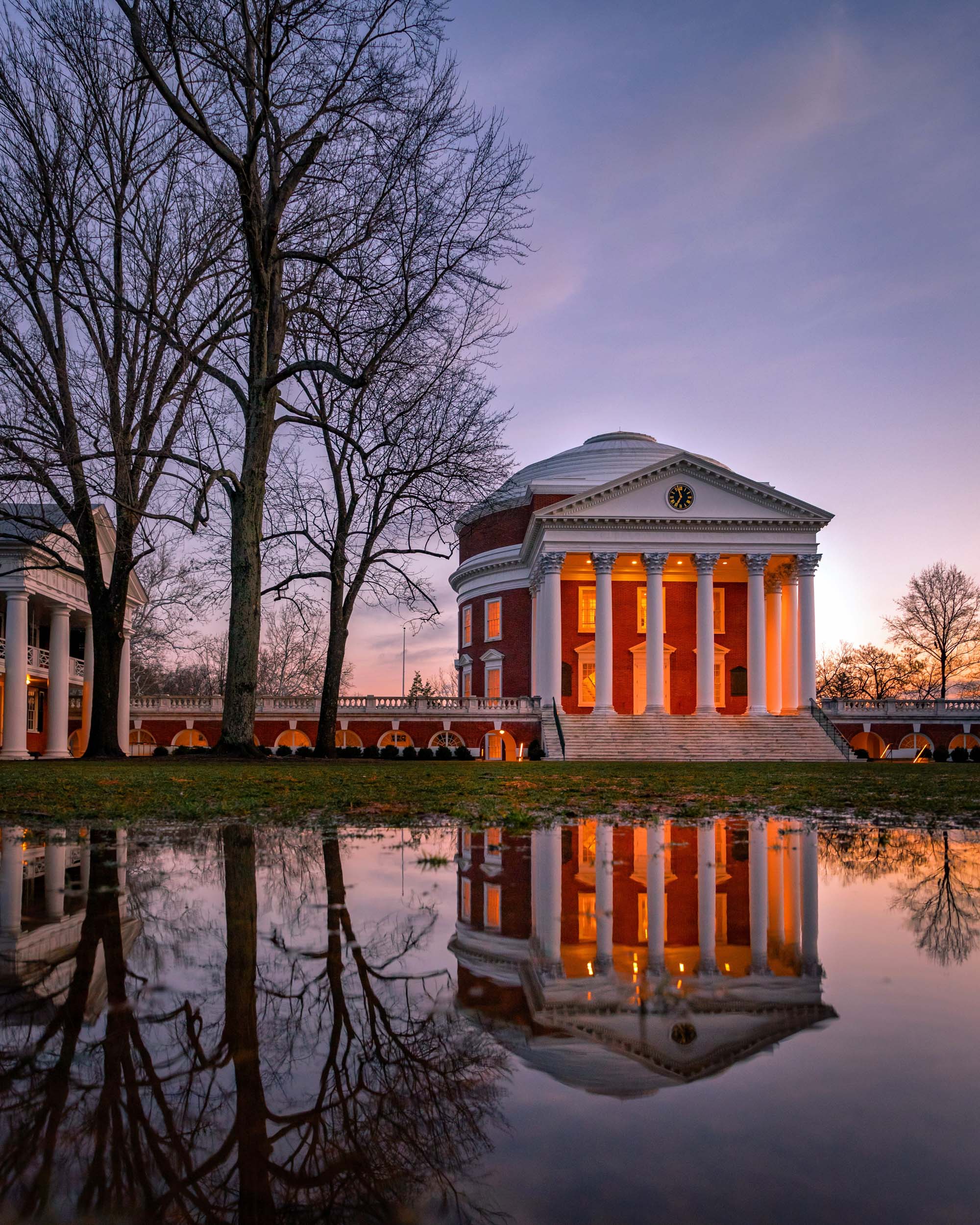 Water on the lawn reflects the Rotunda lit up at dawn
