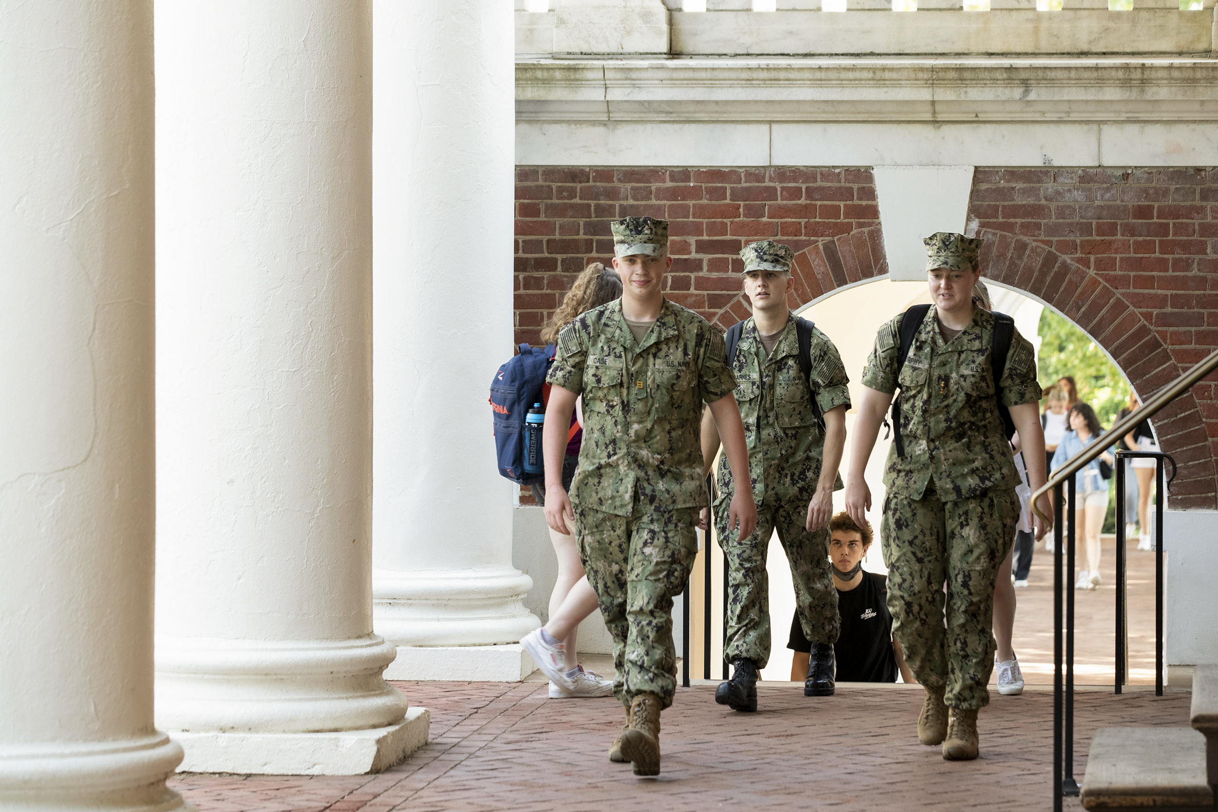 Navy ROTC students, dressed in their uniforms walking on a brick sidewalk