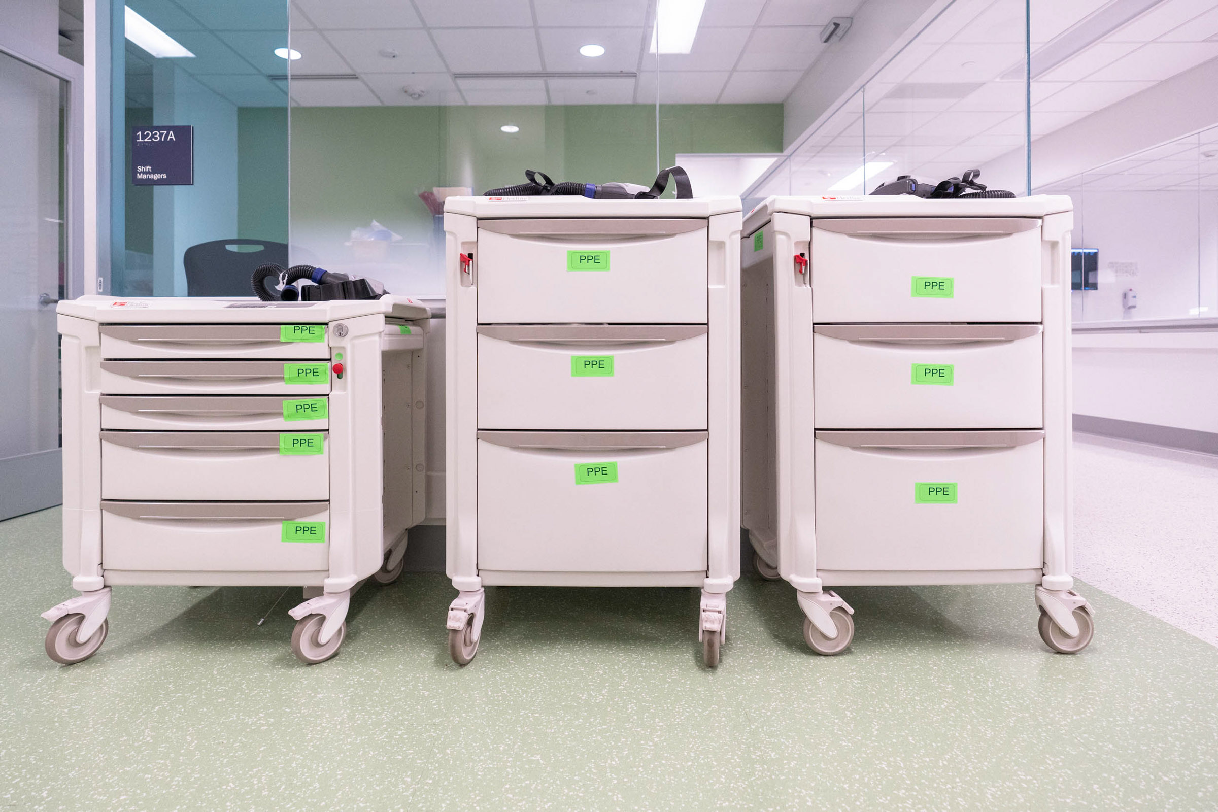 Rolling white medicine cabinets with green labels that read PPE