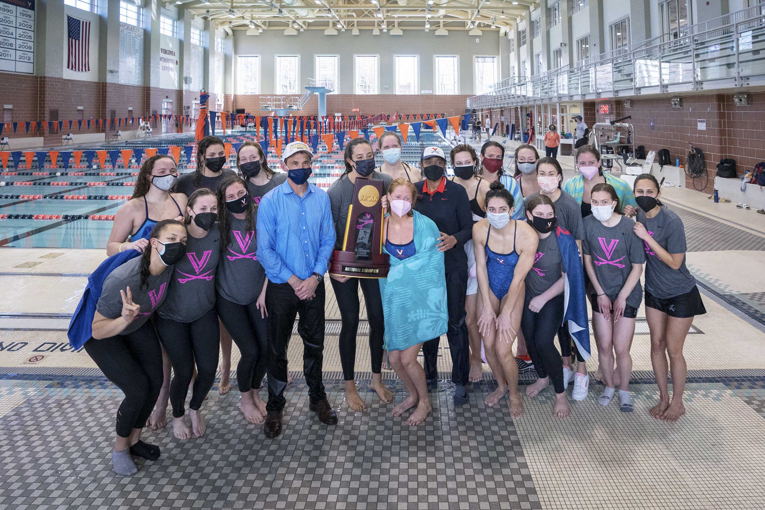 Swimm team gathered together holding their ACC Trophy with President Jim Ryan