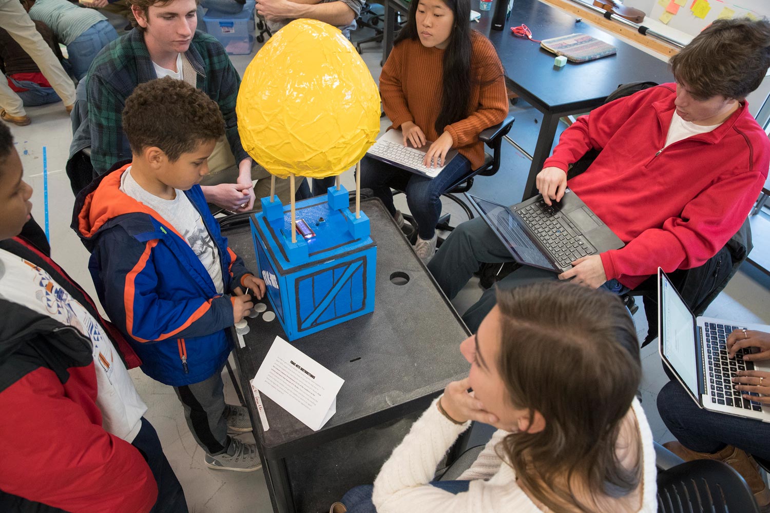 UVA students watch small children interact with a toy