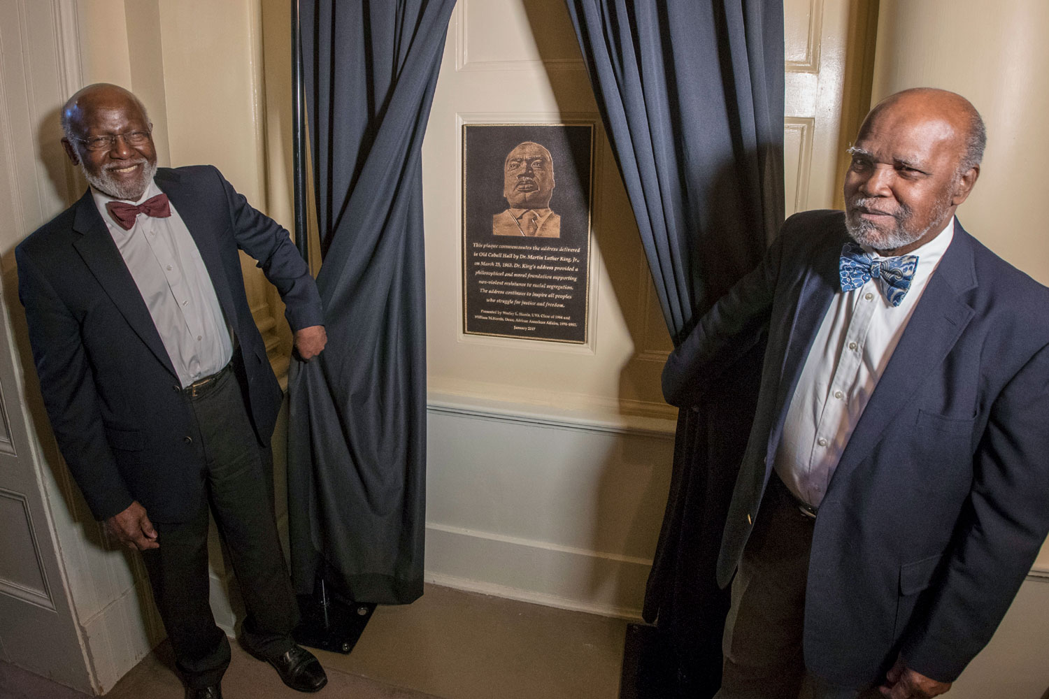 Wesley and William Harris hold blue curtains to show a plaque commemorating Rev. Dr. Martin Luther King Jr.’s appearance at UVA March 25, 1963. 