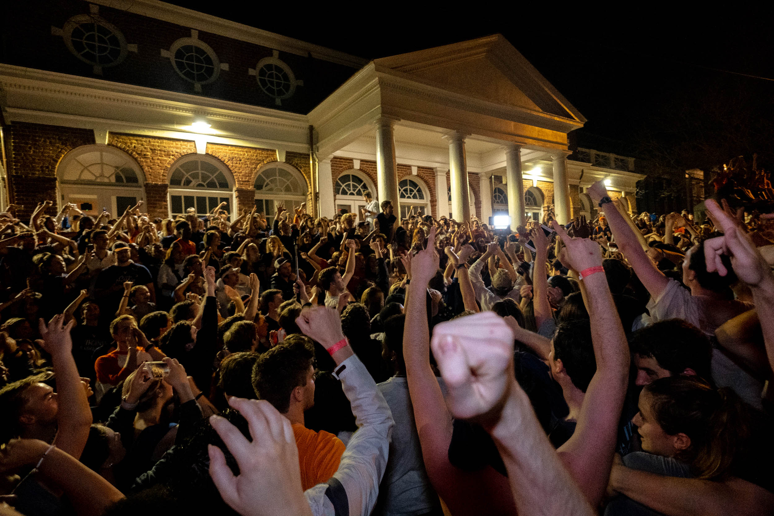 UVA fans outside of a building cheering and celebrating