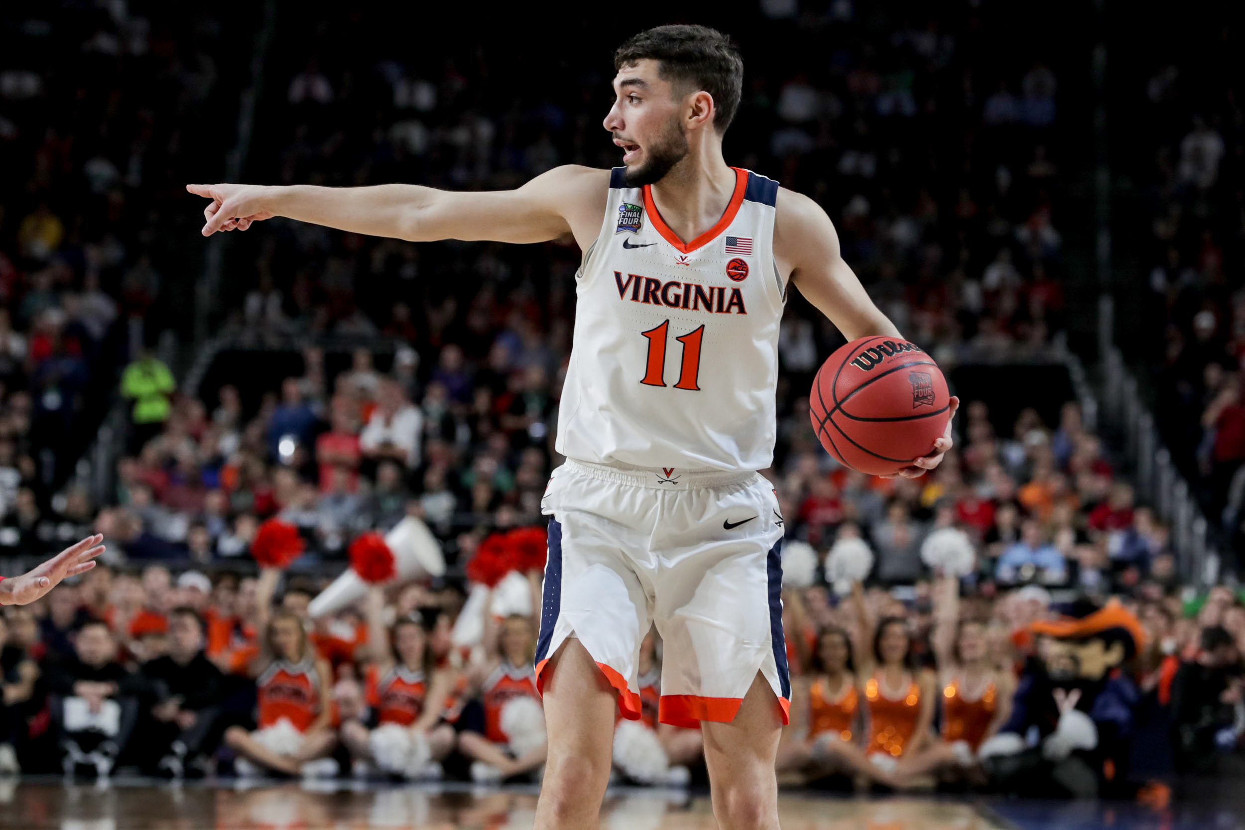 UVA basketball player dribbling the ball and pointing