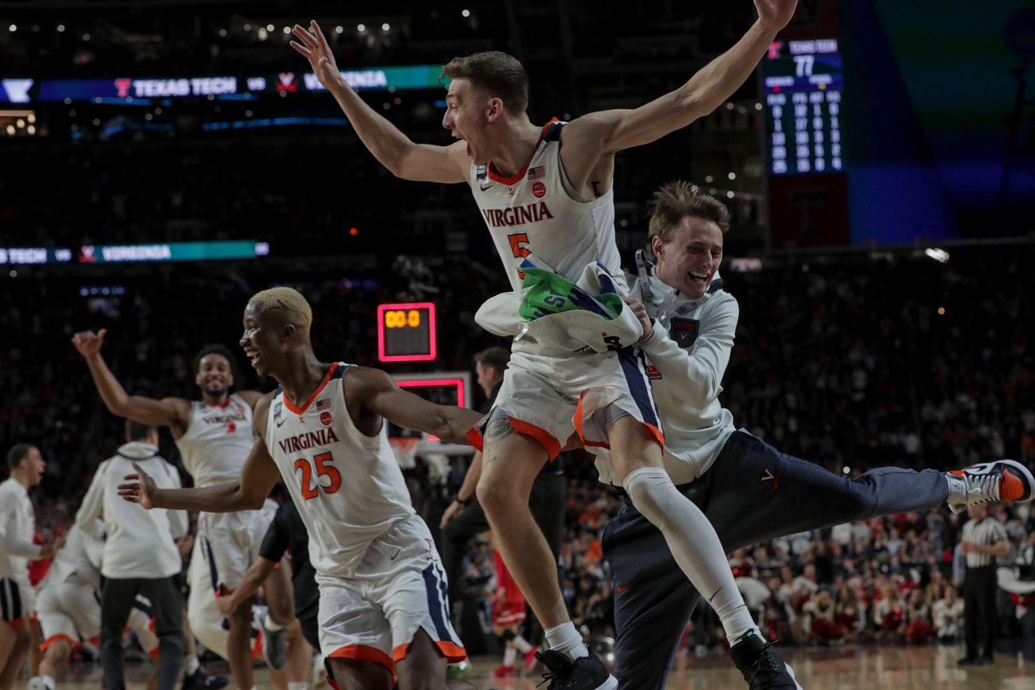 Kyle Guy jumping in the air and being held by teammate after winning the game