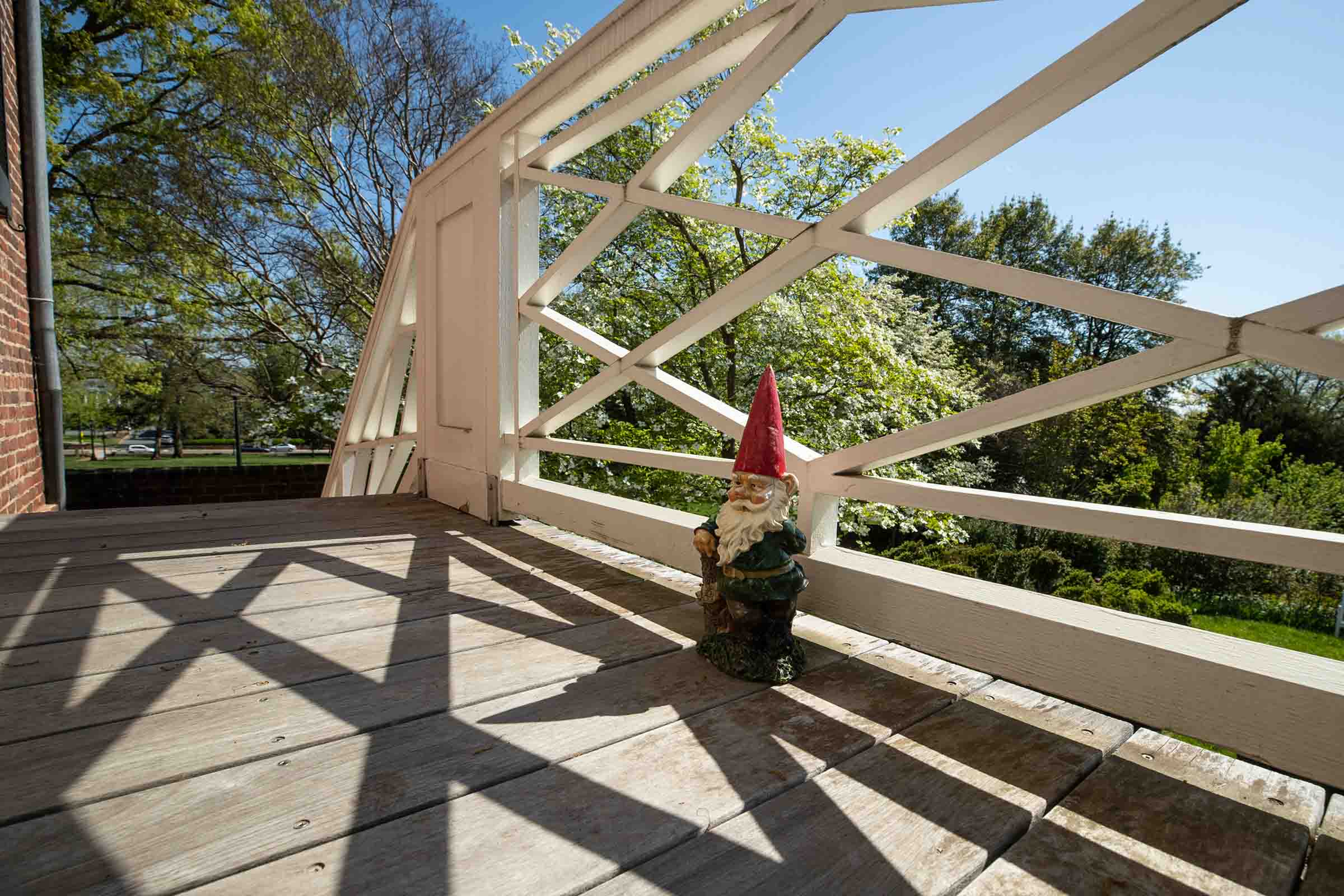 Gnome sitting on a wood deck next to a white railing