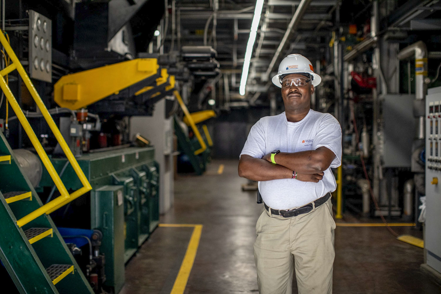 Peter Chege stands with a hardhat in a mechanical room
