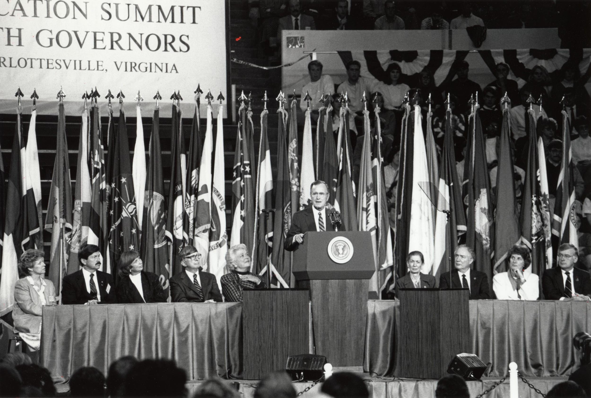 Black and white image of George H.W. Bush standing at a podium talking to a crowd