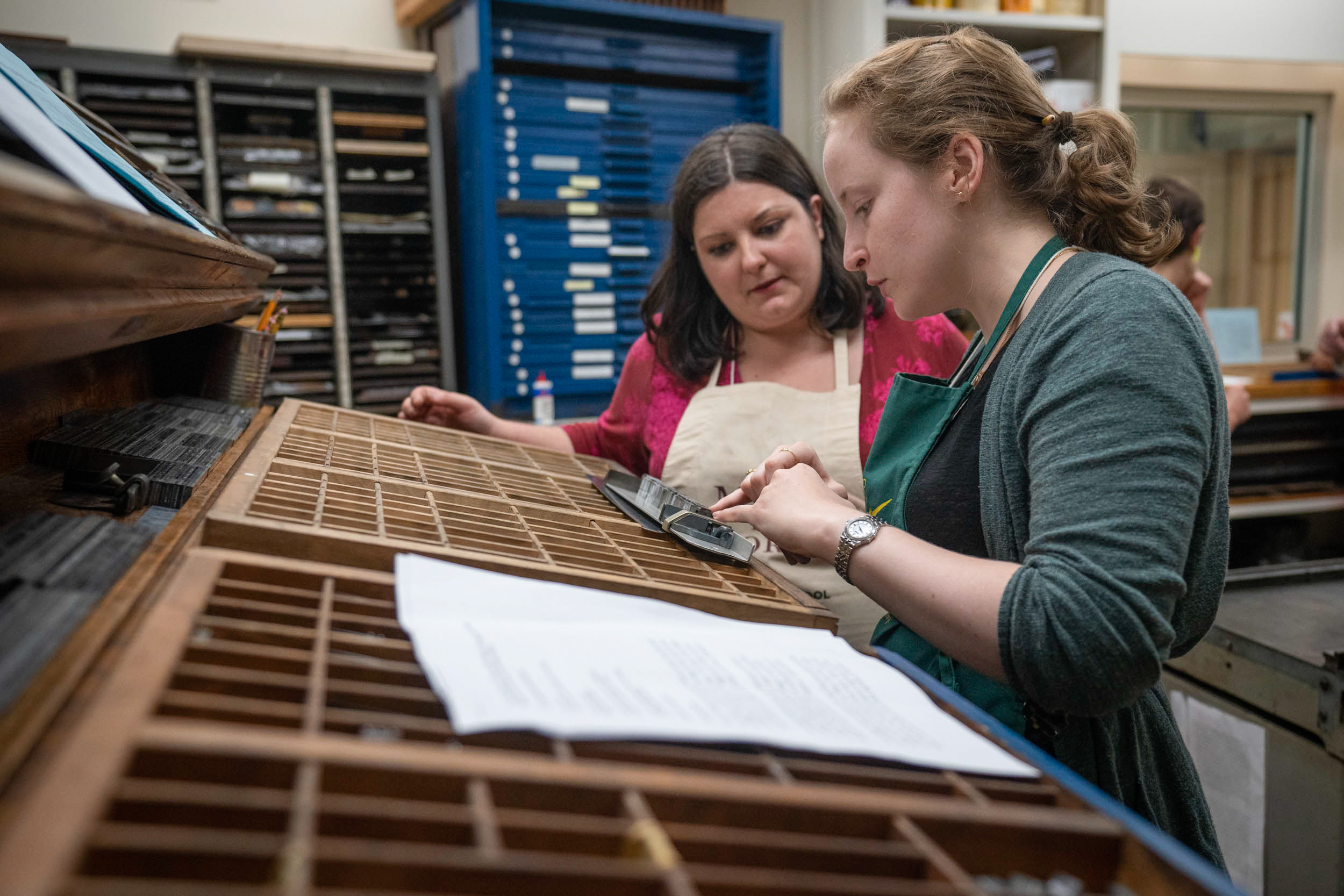 Suzanne Glémot shows Amanda Rogus how the typesetting pieces fit together