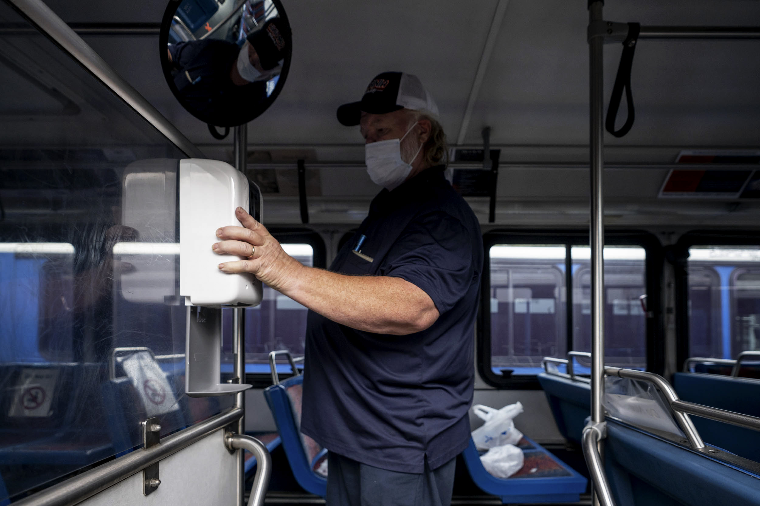 Oscar Goode installs a new hand sanitizer station on a bus