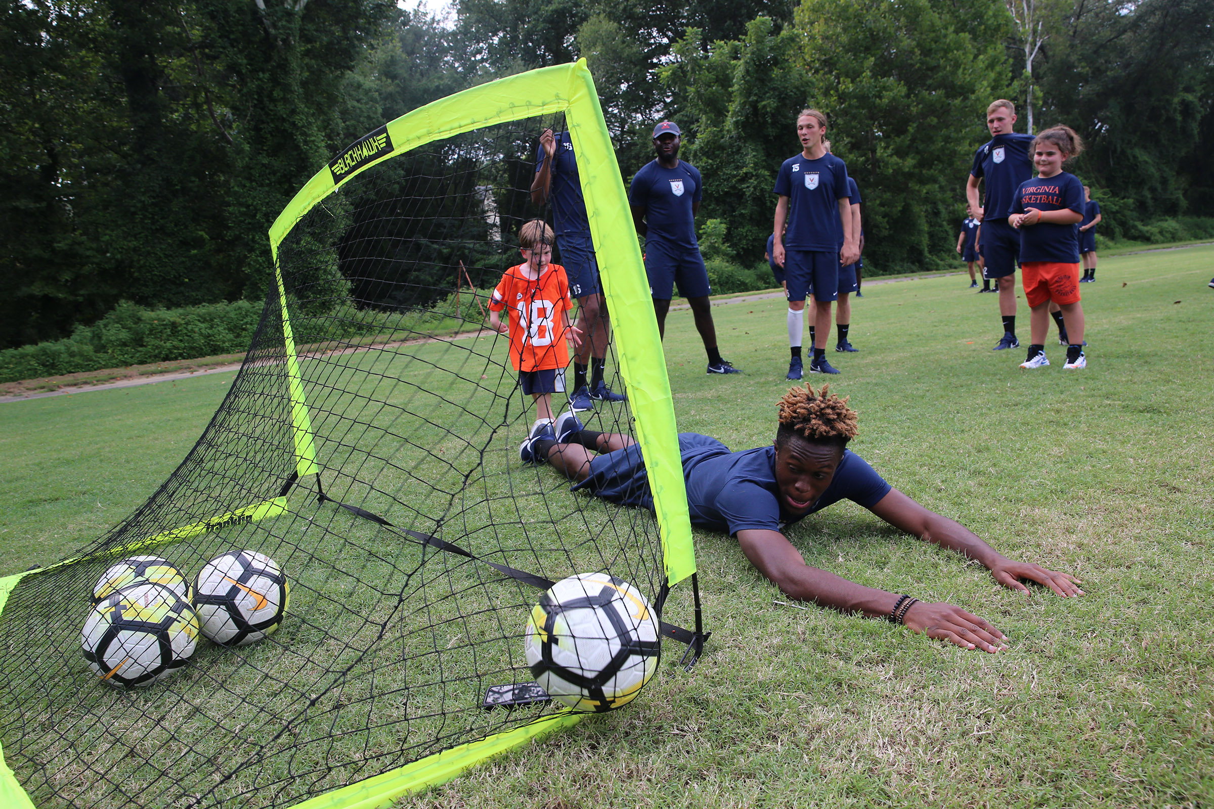 Simeon Okoro lays on the ground as a small kid makes a soccer goal