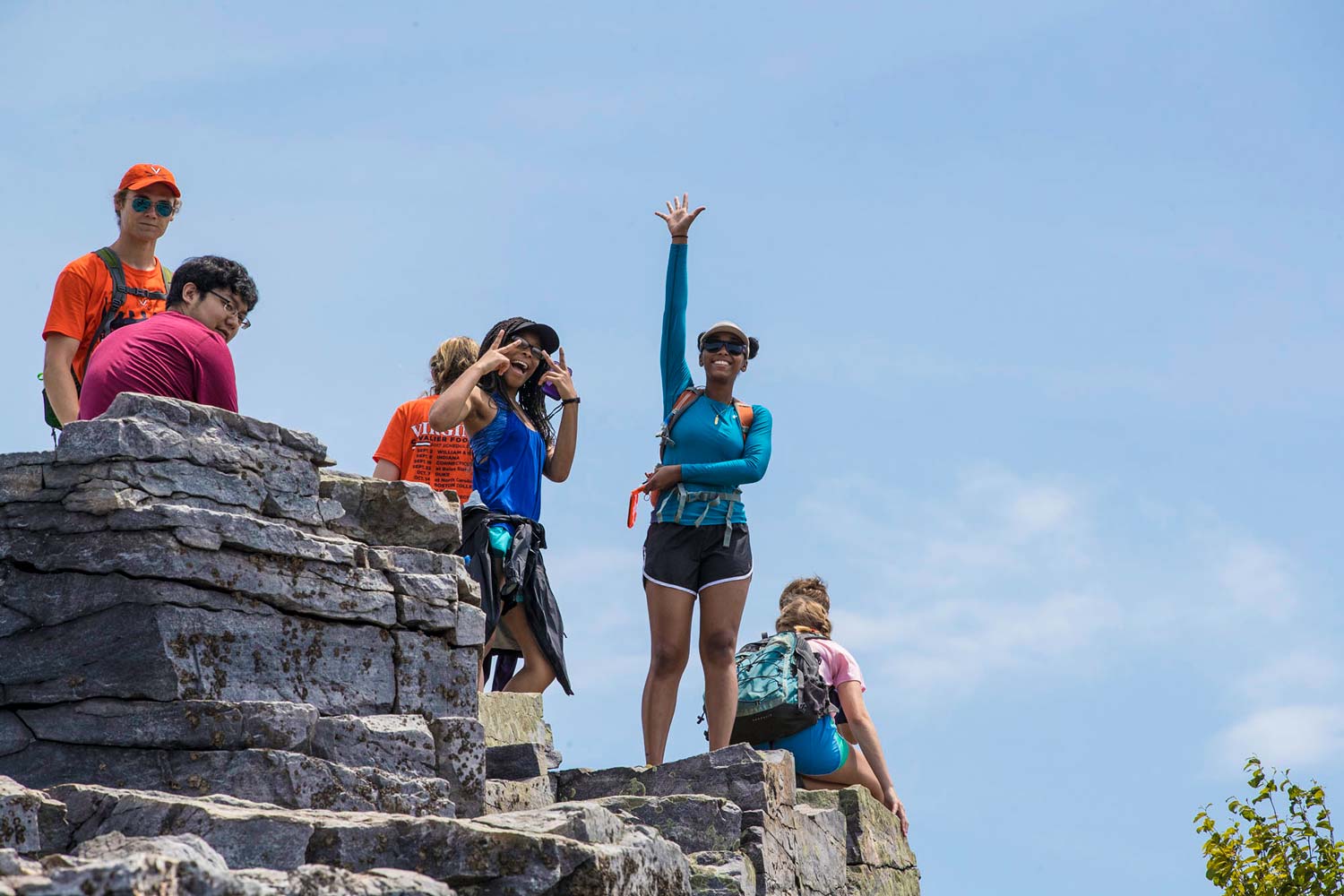 Students celebrate as they stand on the top of boulders