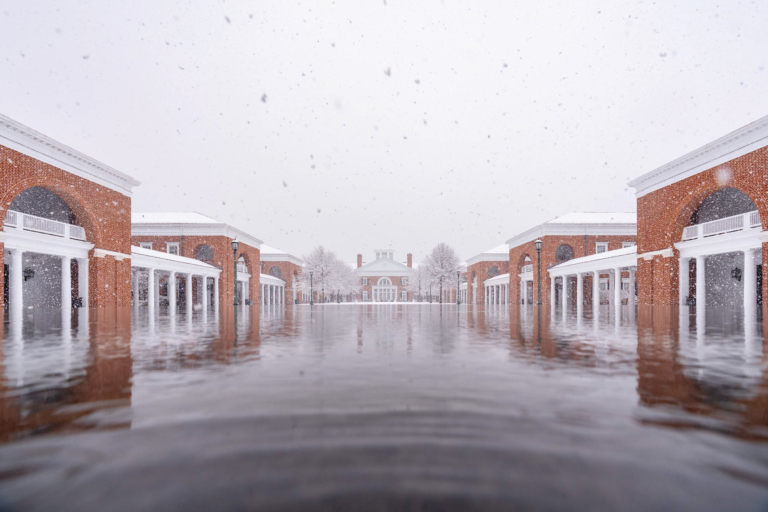 pooled water reflecting the brick buildings that borders it while snow is falling