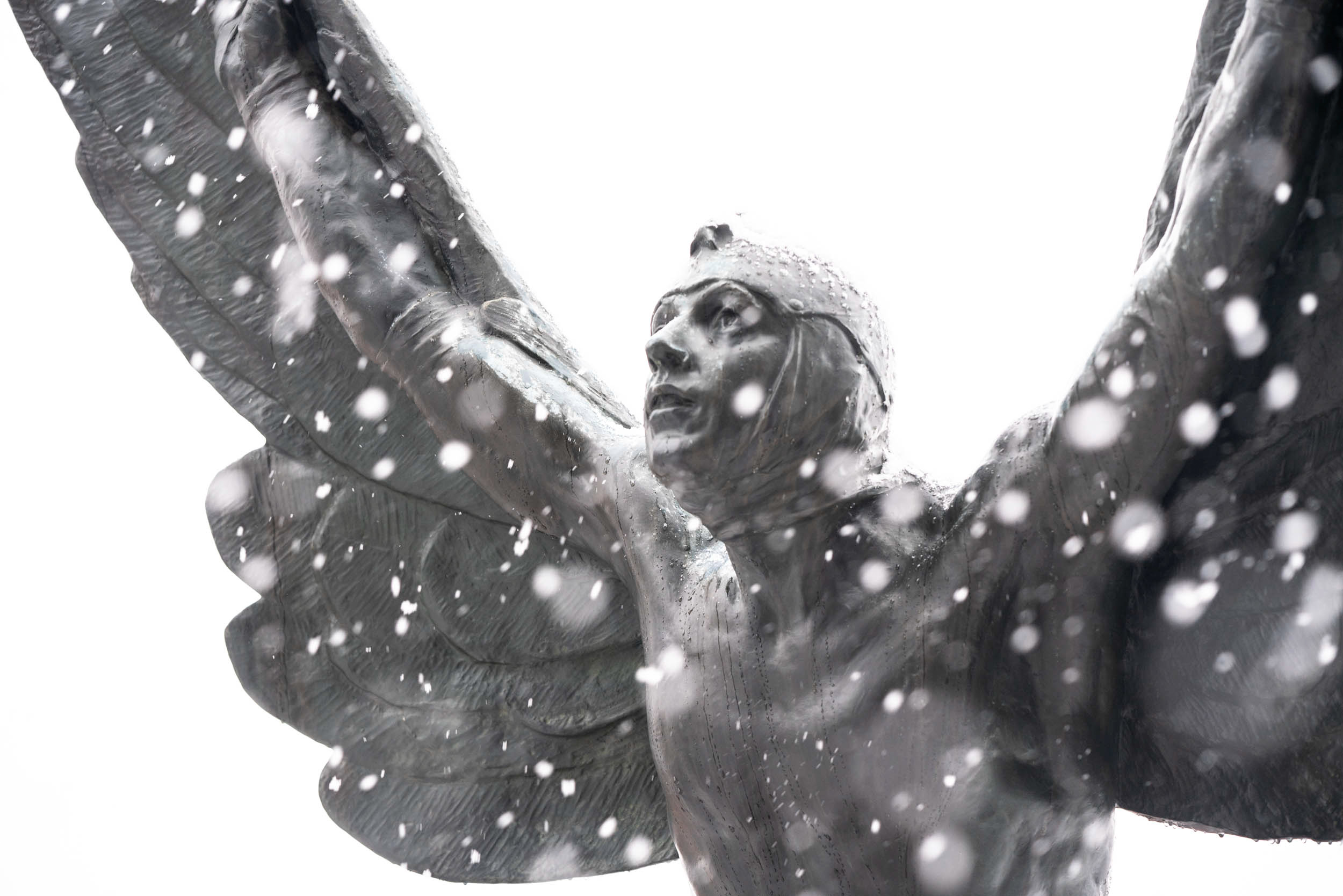 The Aviator against a snowy sky as snow covers him and falls around him