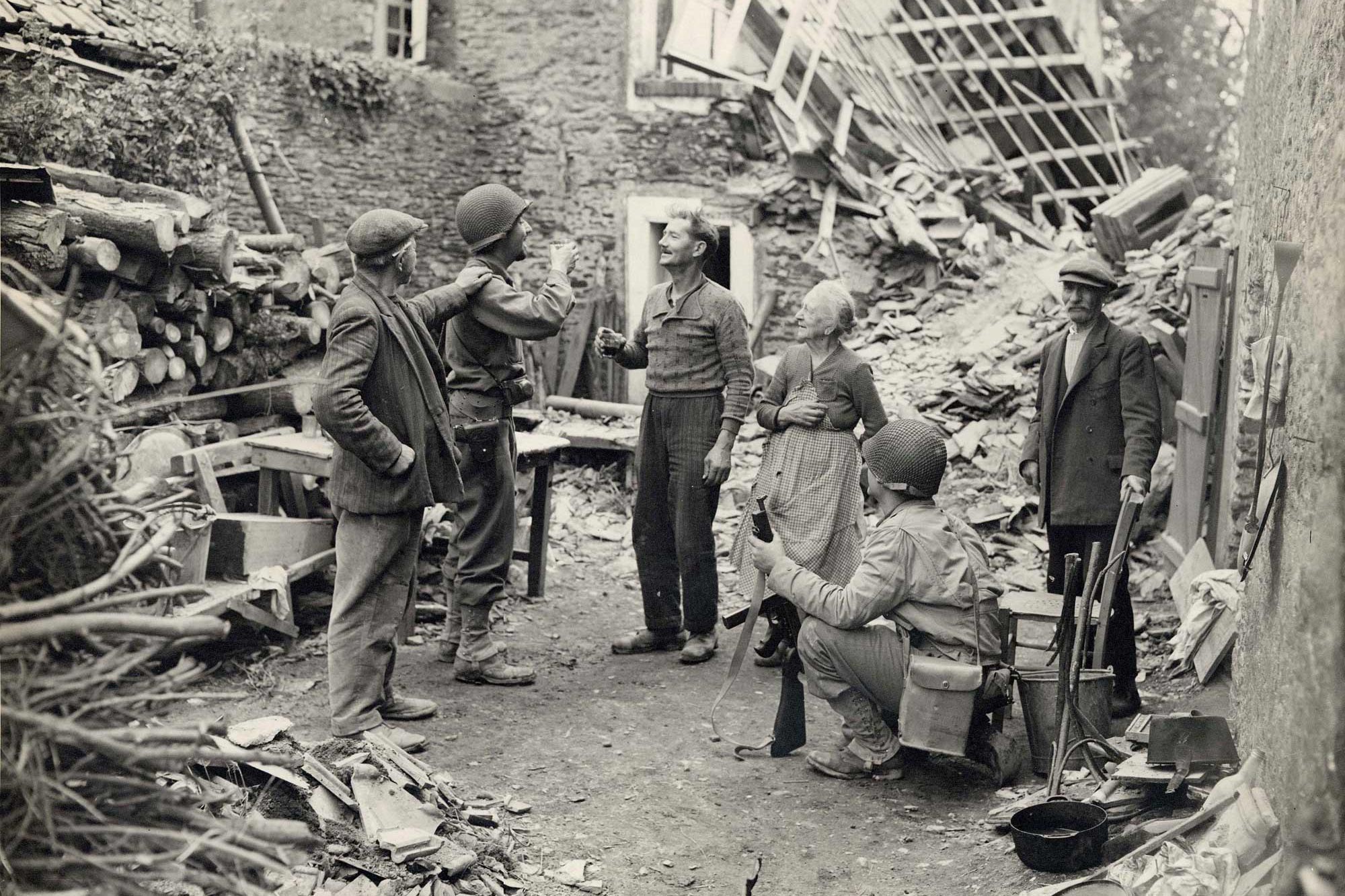 An American Army officer and a French civilian share a toast in the middle of street filled with rubble