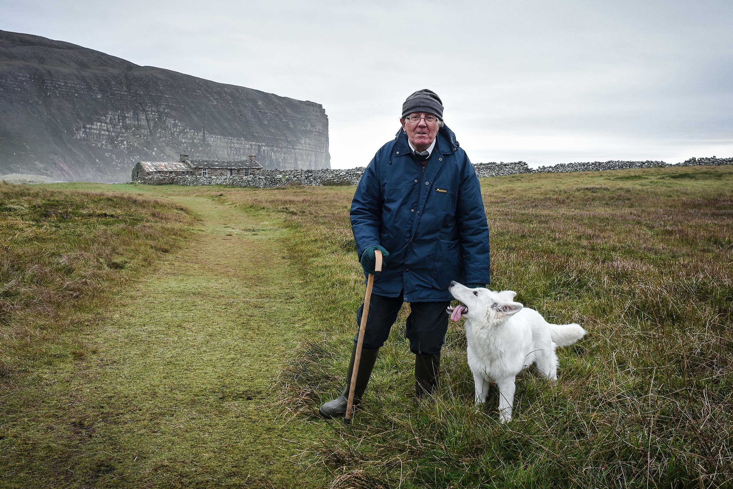 Jeff Clark stands in a field with a white dog