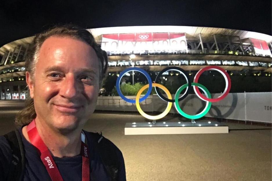 Portrait of Chuck Culpepper standing in front of the Olympic logo in lights