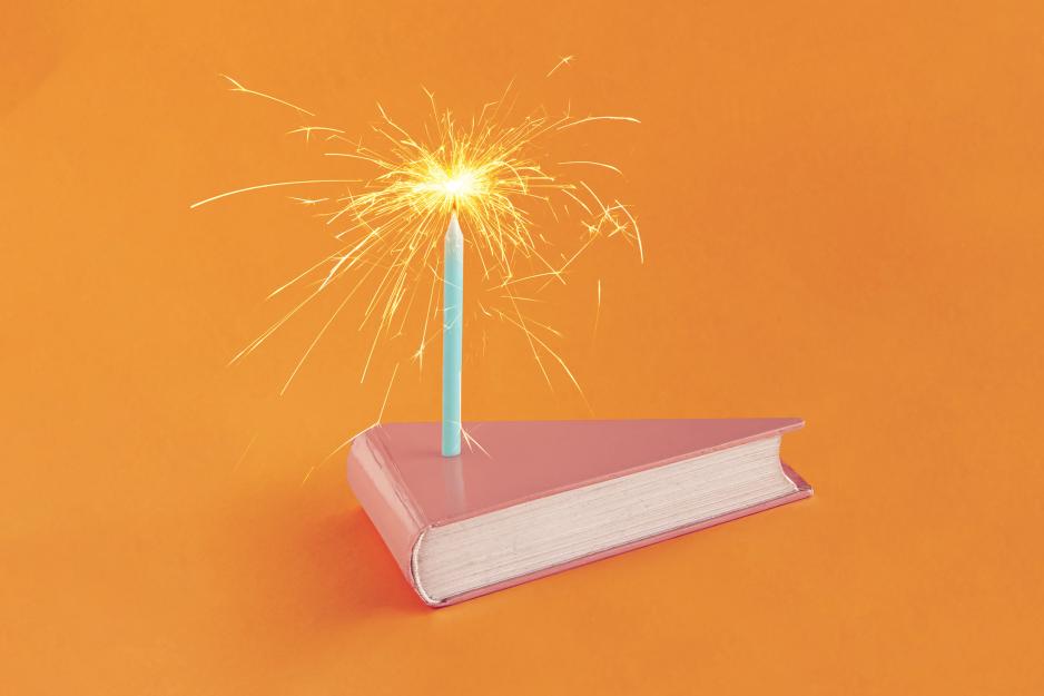 Birthday cake made of a book with a lit candle on it