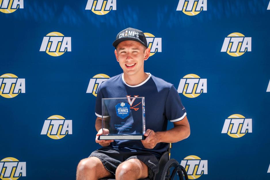 Jacob Wald sitting in front of the Intercollegiate Tennis Association backdrop holding an award
