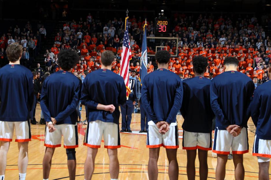 UVA basketball team stand in a line facing the flag of the United States before the game