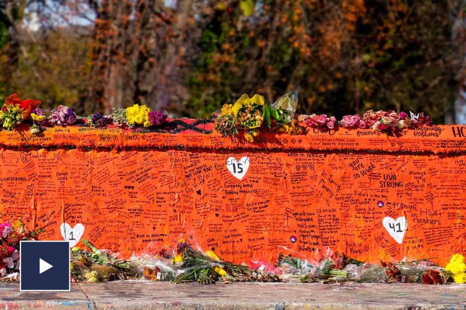 A video play button over a photo of Beta Bridge painted orange with handwriting and flowers all over it